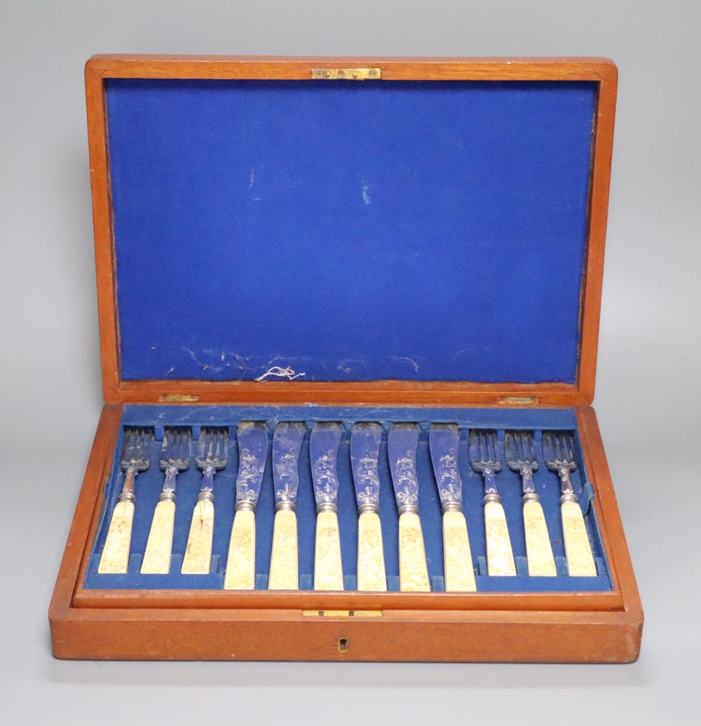 A Victorian set of twelve plated and engraved fish knives and forks, with carved ivory handles, mahogany cased
